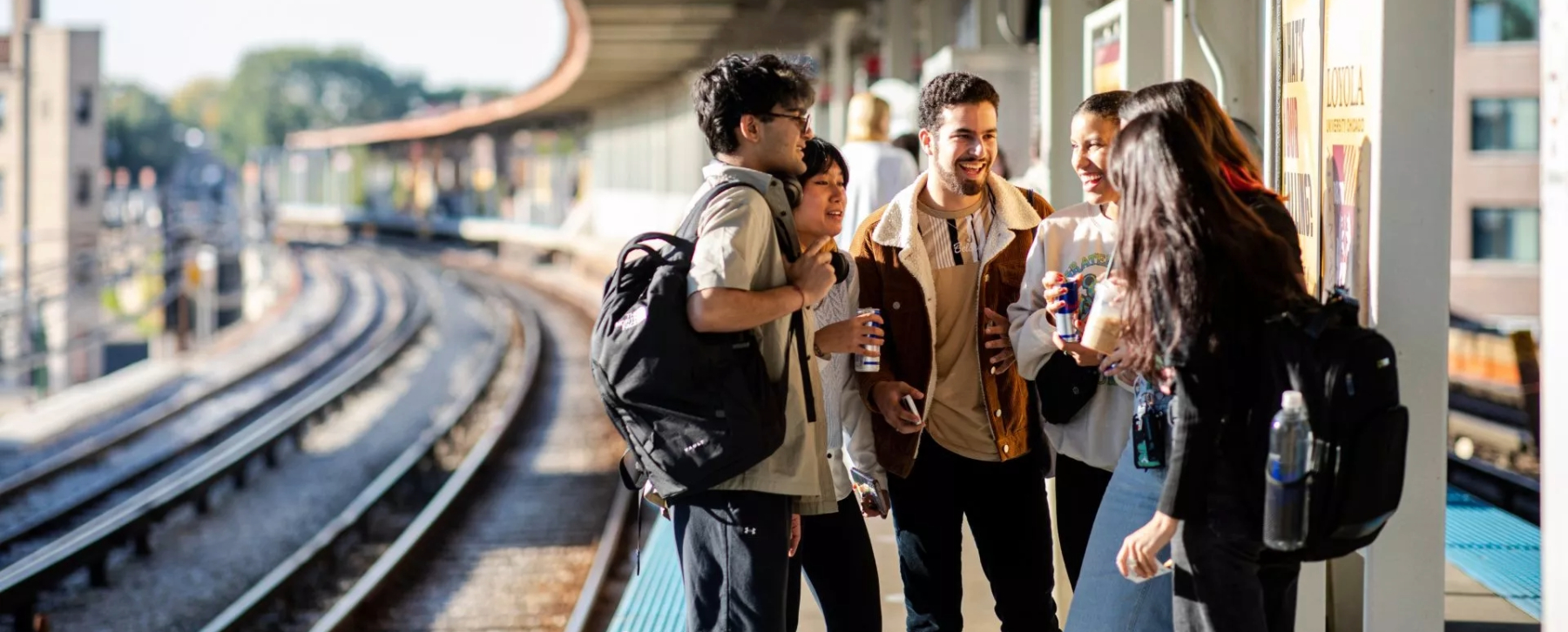 A group of 6 students waiting for the Red Line, smiling and talking.